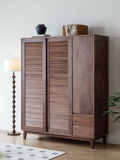 a large wooden cabinet sitting next to a lamp on top of a hard wood floor