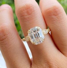 a woman's hand with a ring on it and an emerald stone in the middle