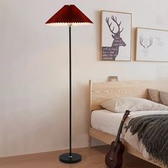 a bed room with a guitar on the floor and a lamp in front of it