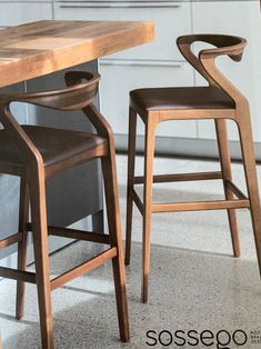 two wooden stools sitting next to each other near a kitchen table and counter top