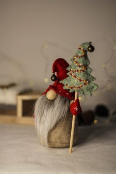 a gnome is holding a christmas tree on a stick