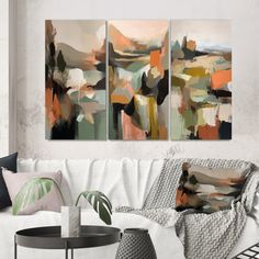 three abstract paintings on the wall above a couch in a living room with white walls