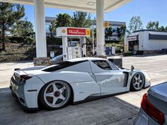 a white sports car parked at a gas station