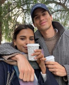 a man and woman holding coffee cups in their hands