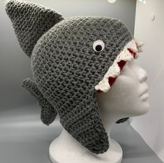 a crocheted shark hat on a mannequin head with eyes and mouth