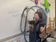 a woman wearing a face mask while standing in front of a whiteboard