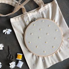 a white bag with flowers on it next to scissors, thread and other crafting supplies