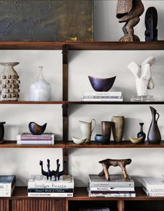 shelves with vases, books and sculptures on them