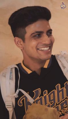 a young man smiling and holding a baseball glove