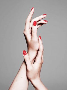 two hands with red manicures holding each other's fingers in the air