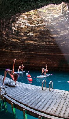 some people are in the water on surfboards and one person is doing a handstand