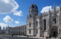 people are walking around in front of a large building with towers and arches on it