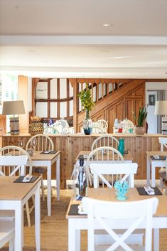 an empty restaurant with white chairs and wooden tables in front of the counter area is shown