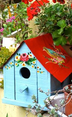 a blue birdhouse sitting on top of a table next to potted plants