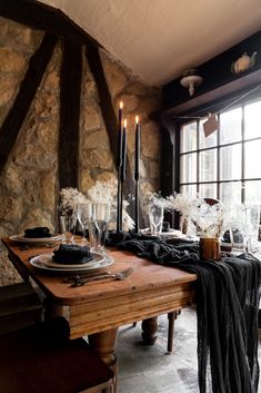 a dining room table with candles and black linens on it, along with other decorations