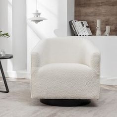 a white chair sitting in a living room next to a table with books on it