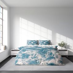 a bed with blue and white comforters in a room next to a window,