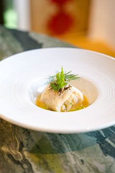 a white plate topped with food on top of a marble countertop next to a vase