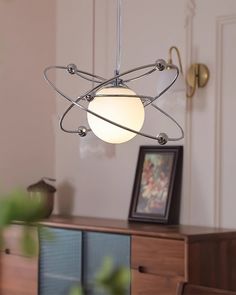 a light fixture hanging from the ceiling in a living room with a wooden dresser and sideboard