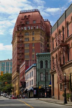 a city street lined with tall buildings under a cloudy blue sky