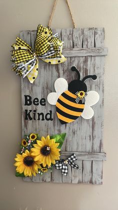 a wooden sign hanging on the side of a wall with sunflowers and a bee