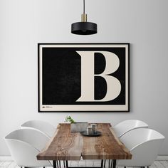 a dining room table with white chairs and a framed letter b on the wall above it