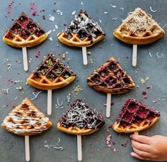 several waffles with toppings on them sitting on top of a blue surface