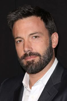 a close up of a person wearing a suit and tie with a goatee beard