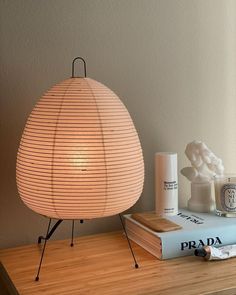 a lamp sitting on top of a wooden table next to a stack of books and a vase