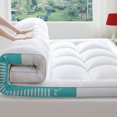 a person is placing an inflatable mattress on top of a bed that's next to a window