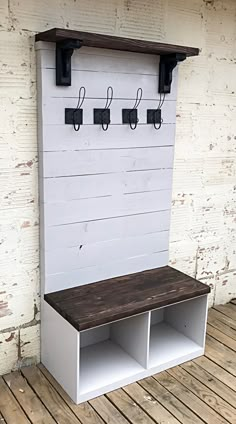 a white bench sitting on top of a wooden floor next to a wall with hooks