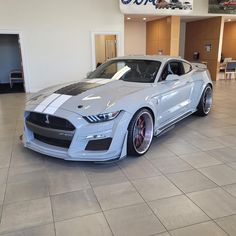 a white car is parked in a showroom