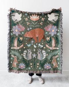 a person holding up a tapestry with animals on it