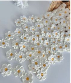 white and yellow flowers are scattered on the table next to a basket full of straw