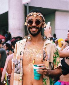 a man with no shirt on holding a cup in his hand and wearing gold jewelry