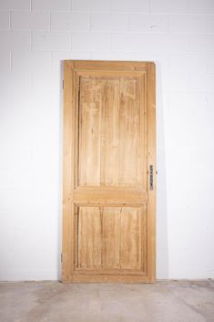 an open wooden door sitting on top of a cement floor next to a white wall