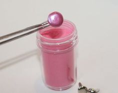 a pink liquid in a small jar next to a pair of screwdrivers