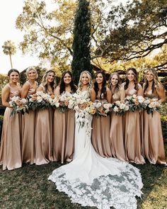 a group of women standing next to each other in front of a tree with flowers