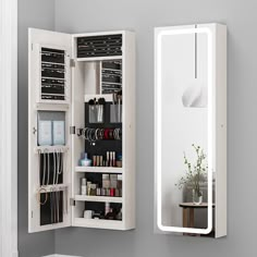 an open medicine cabinet next to a mirror with jewelry on it and a potted plant in the corner