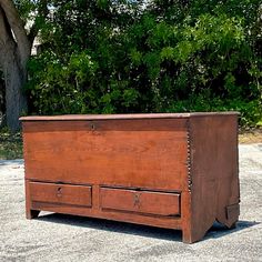 an old wooden dresser sitting in the middle of a parking lot next to a tree