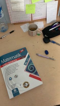 a book sitting on top of a wooden table next to a cup of coffee and other office supplies