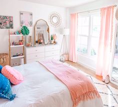 a bedroom with pink and blue decor on the walls, white bedding, and windows