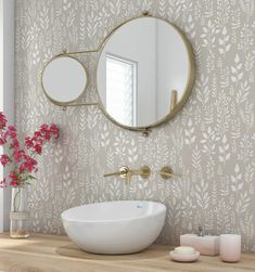 a white sink sitting under a round mirror next to a wall mounted faucet