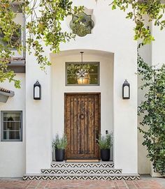 a white house with a wooden door and two planters