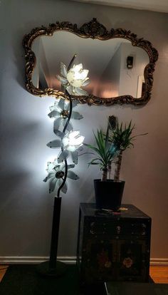 a mirror sitting on top of a wall next to a potted plant and a lamp