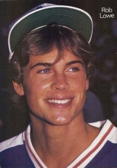 a close up of a person wearing a baseball cap and smiling at the camera with his eyes wide open