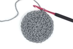 the crochet ball is being worked on with a knitting needle and yarn hook