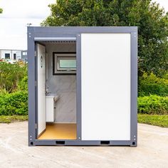 an outhouse with a toilet and sink in the middle of a lot next to some bushes