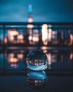 a crystal ball sitting on top of a reflective surface in front of a cityscape