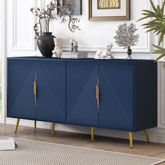 a blue sideboard with gold accents in a living room next to a potted plant